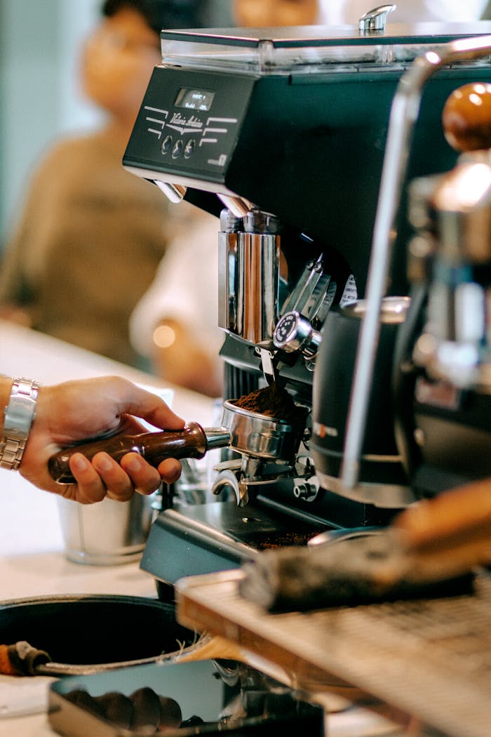 Barista using espresso machine to brew fresh coffee in a Baku café.